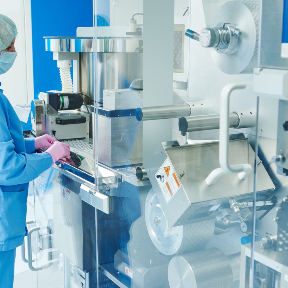 Pharmaceutics. Pharmaceutical industry worker operates blister and cartoning packaging machine at factory