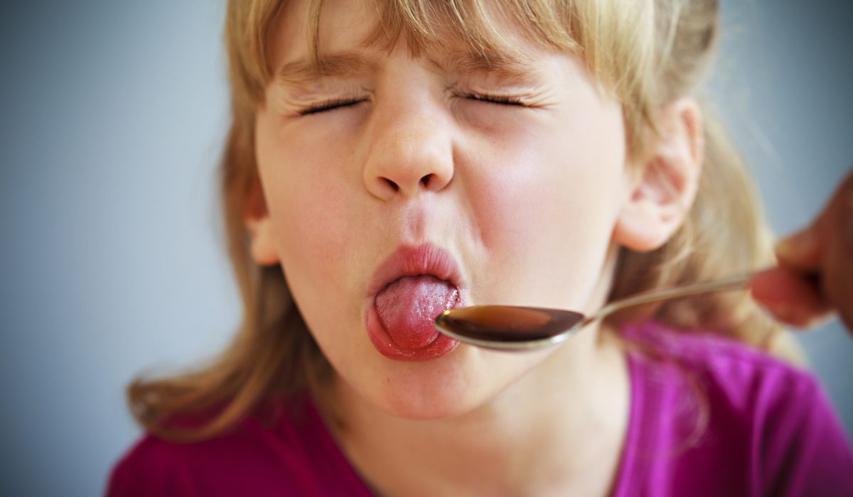 Yuck! Young girl pulls a face rather than swallow the bitter medicine she's offered on a spoon.